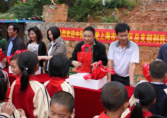 张云江（左4）在2012年关李完小同心助学活动上为学校的孩子们分发文具